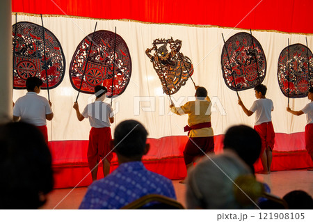 Four player men stand with perform grand shadow play in front of white screen and audience look and happy to see the show. 121908105