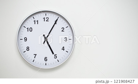 Minimalist White Clock with Silver Frame Striking 17.05/05.05 on White Background. Perfect for Time Management and Corporate Campaigns Minimalist White Clock with Silver Frame Striking 17.05/05.05 on White Background. Perfect for Time Management and Corporate Campaigns 121908427