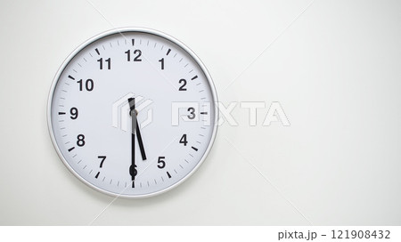 Minimalist White Clock with Silver Frame Striking 17.30/05.30 on White Background. Perfect for Time Management and Corporate Campaigns 121908432