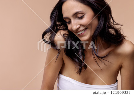 Studio portrait of a charming brunette woman in a white top with beautiful wavy hair Studio portrait of a charming brunette woman in a white top with beautiful wavy hair 121909325