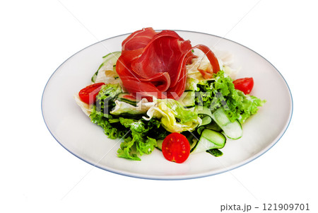 Salad with ham and vegetables lettuce, cabbage, tomato. Jamon jerky on a white plate isolated on a white background. Meat with vegetables 121909701
