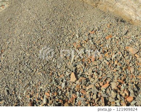 texture of small sharp stone, crumbled copper-colored rock that has rolled down a mountain in bulk, stone chips scattered on a natural slope of a cliff, small fraction of crushed stone texture of small sharp stone, crumbled copper-colored rock that has rolled down a mountain in bulk, stone chips scattered on a natural slope of a cliff, small fraction of crushed stone 121909824