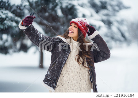 Young woman taking selfie in winter forest. Holidays, rest, travel concept. 121910184