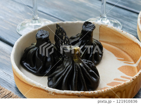 Black khinkali, Georgian seafood chinkali, spicy dumplings with minced meat also called dimsum Black khinkali, Georgian seafood chinkali, spicy dumplings with minced meat also called dimsum 121910836