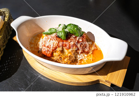 Lasagna portion, oven baked lasagne, pasta layers with cheese, minced meat, tomato in sunny summer day Lasagna portion, oven baked lasagne, pasta layers with cheese, minced meat, tomato in sunny summer day 121910962