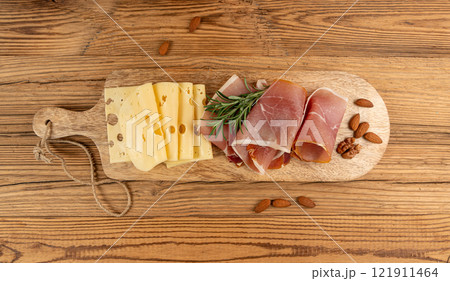Cheese plate with prosciutto, jamon cut, parma ham, serrano slices, cured iberico closeup, cheese board 121911464