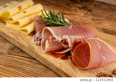 Cheese plate with prosciutto, jamon cut, parma ham, serrano slices, cured iberico closeup, cheese board Cheese plate with prosciutto, jamon cut, parma ham, serrano slices, cured iberico closeup, cheese board 121911468