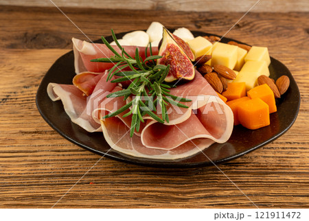 Cheese plate with prosciutto, jamon cut, parma ham, serrano slices, cured iberico closeup, cheese board Cheese plate with prosciutto, jamon cut, parma ham, serrano slices, cured iberico closeup, cheese board 121911472