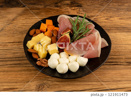 Cheese plate with prosciutto, jamon cut, parma ham, serrano slices, cured iberico closeup, cheese board 121911473