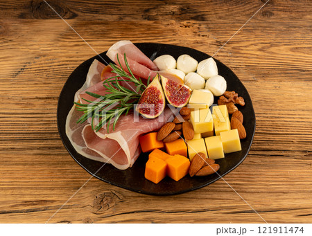 Cheese plate with prosciutto, jamon cut, parma ham, serrano slices, cured iberico closeup, cheese board Cheese plate with prosciutto, jamon cut, parma ham, serrano slices, cured iberico closeup, cheese board 121911474
