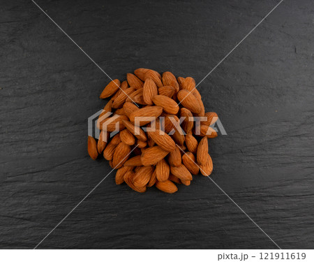 Almonds pile, nut group, whole almond seeds, brown scattered fruit kernels, dry raw nuts on black Almonds pile, nut group, whole almond seeds, brown scattered fruit kernels, dry raw nuts on black 121911619