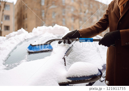 Portrait of smiling man cleaning snow off his car during winter snowfall. Transport, weather concept Portrait of smiling man cleaning snow off his car during winter snowfall. Transport, weather concept 121911735