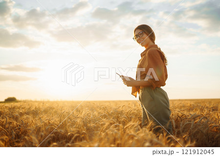Young Female farmer with tablet in the field. Agriculture, gardening, business or ecology concept. Young Female farmer with tablet in the field. Agriculture, gardening, business or ecology concept. 121912045