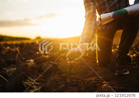 Farm owner checks quality of soil with his hands with tablet and checks fertility before sowing. 121912076