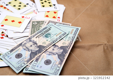 A pile of dollars and a deck of poker cards spread out on a table A pile of dollars and a deck of poker cards spread out on a table 121912142