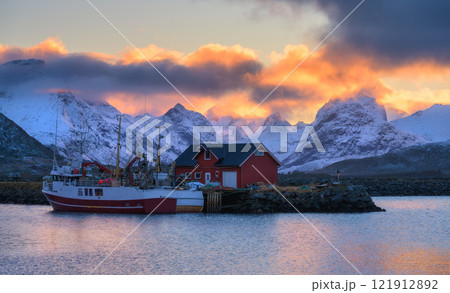 Red fishing boats on the sea, snowy mountains at colorful sunset 121912892