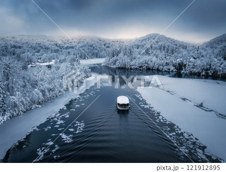 Aerial drone view of boat in frozen lake at sunset in winter Aerial drone view of boat in frozen lake at sunset in winter 121912895
