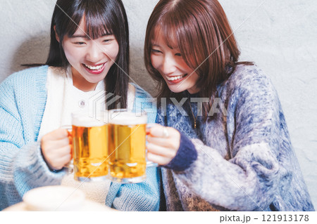 カニ鍋を前に乾杯をする若い女性二人【撮影協力・海鮮居酒屋 魚魯こ】 カニ鍋を前に乾杯をする若い女性二人【撮影協力・海鮮居酒屋 魚魯こ】 121913178