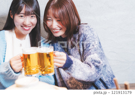 カニ鍋を前に乾杯をする若い女性二人【撮影協力・海鮮居酒屋　魚魯こ】 121913179