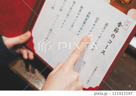 メニューを見て選ぶ女性客の手【撮影協力・海鮮居酒屋 魚魯こ】 メニューを見て選ぶ女性客の手【撮影協力・海鮮居酒屋 魚魯こ】 121913197
