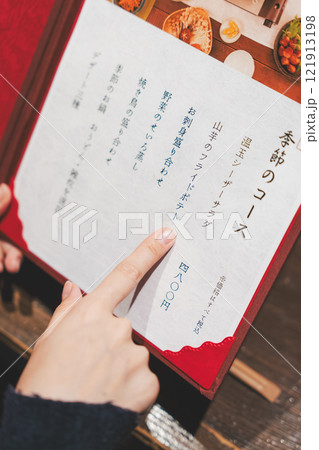 メニューを見て選ぶ女性客の手【撮影協力・海鮮居酒屋 魚魯こ】 メニューを見て選ぶ女性客の手【撮影協力・海鮮居酒屋 魚魯こ】 121913198