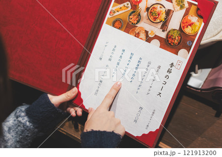 メニューを見て選ぶ女性客の手【撮影協力・海鮮居酒屋　魚魯こ】 121913200