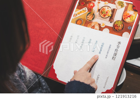 メニューを見て選ぶ女性客の手【撮影協力・海鮮居酒屋 魚魯こ】 メニューを見て選ぶ女性客の手【撮影協力・海鮮居酒屋 魚魯こ】 121913216