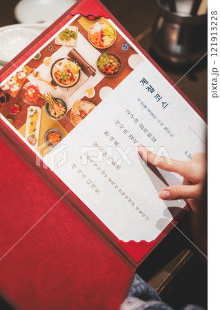 メニューを見て選ぶ女性客の手【撮影協力・海鮮居酒屋　魚魯こ】 121913228