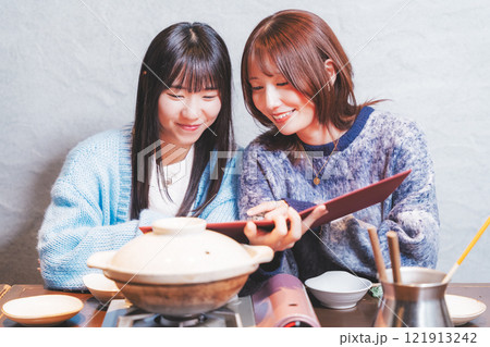 カニ鍋を前に次の注文を考える若い女性二人【撮影協力・海鮮居酒屋　魚魯こ】 121913242