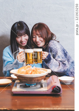 カニ鍋を前に乾杯をする若い女性二人【撮影協力・海鮮居酒屋　魚魯こ】 121913250