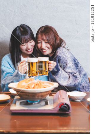 カニ鍋を前に乾杯をする若い女性二人【撮影協力・海鮮居酒屋　魚魯こ】 121913251