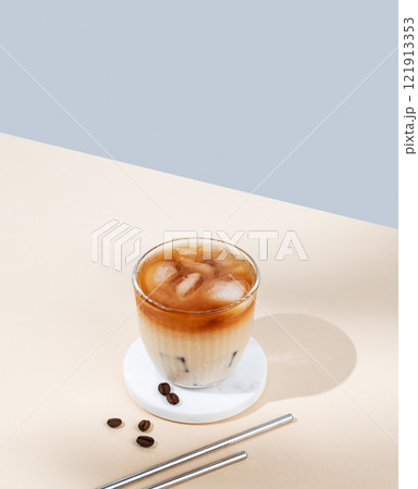 Iced coffee latte in a glass with milk on a yellow and blue background with coffee beans Iced coffee latte in a glass with milk on a yellow and blue background with coffee beans 121913353