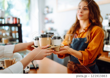 Close-up of a female barista's hands giving out a to-go drink order. Small business. 121913863