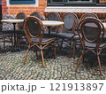 Round tables and chairs with bent backs and legs await visitors on the cafe's summer terrace 121913897