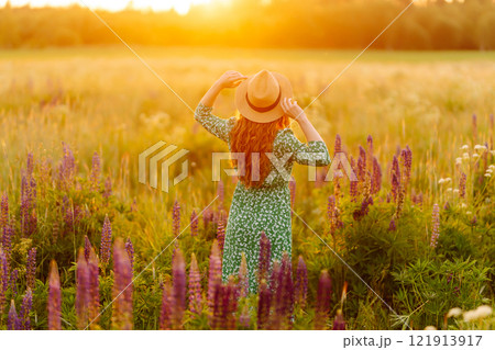 A beautiful woman with a bouquet of lupins, collects flowers, inhales fresh floral air. 121913917