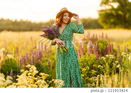 A beautiful woman with a bouquet of lupins, collects flowers, inhales fresh floral air. A beautiful woman with a bouquet of lupins, collects flowers, inhales fresh floral air. 121913924