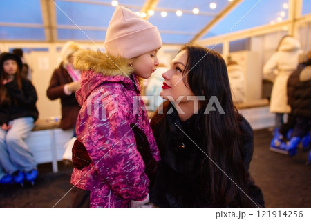 Mother and daughter share a joyful moment at a winter skating rink 121914256