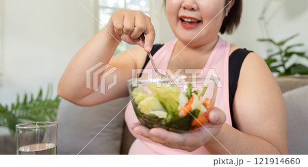 Healthy eating journey overweight woman enjoying fresh food to lose weight in a cozy home setting 121914660