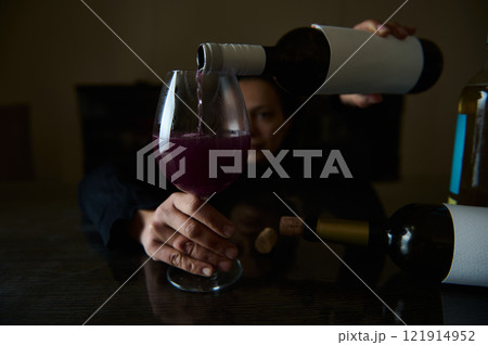 Wine being poured into a glass with a person in the background 121914952