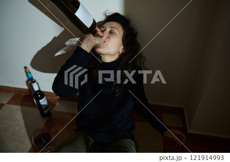 Person in dramatic scene with alcohol consumption in an indoor setting Person in dramatic scene with alcohol consumption in an indoor setting 121914993