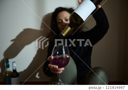 Woman pouring wine into a glass in a dimly lit setting 121914997