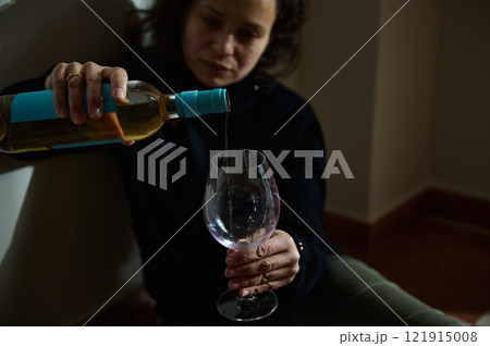 Woman pouring white wine into a glass in a contemplative environment 121915008