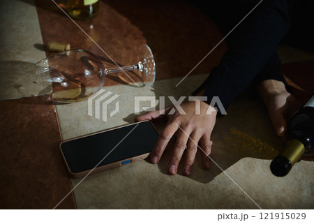 Broken wine glass on the floor with mobile phone and hand visible Broken wine glass on the floor with mobile phone and hand visible 121915029