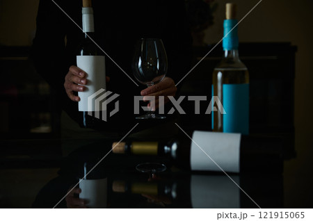 Dark mood scene featuring wine bottles and empty glasses on a table 121915065