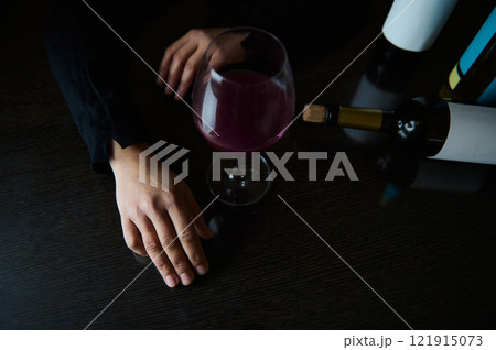Person Resting Hand Near a Glass of Red Wine on a Table Person Resting Hand Near a Glass of Red Wine on a Table 121915073