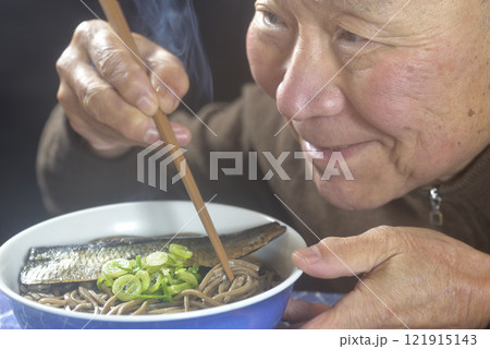 丼に湯気の立ち昇るニシン蕎麦を笑顔で食べる老人 121915143