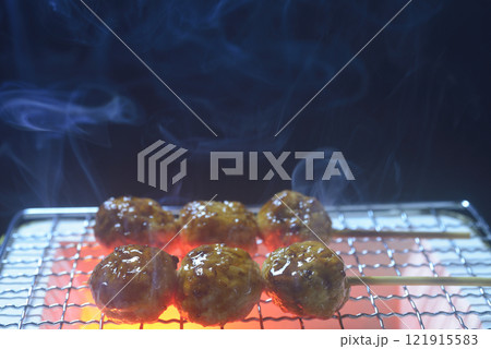煙の立ち昇る七輪で鶏つくねを焼く 121915583