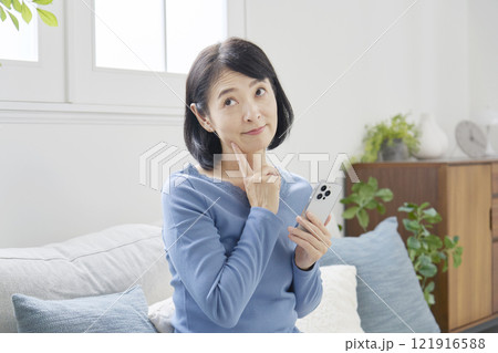 スマホを持って考える中年女性　リビング 121916588