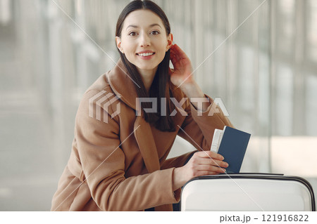 Woman at the airport. Girl with suitcase. Lady in a brown coat. 121916822