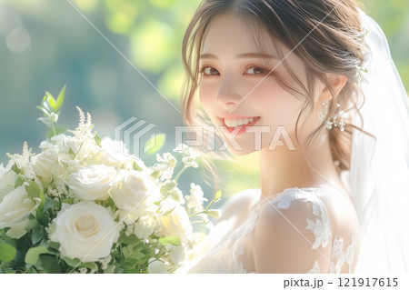 ブーケの花束を手に持ち、ウェディングドレスを着た笑顔が可愛い若い女性 121917615